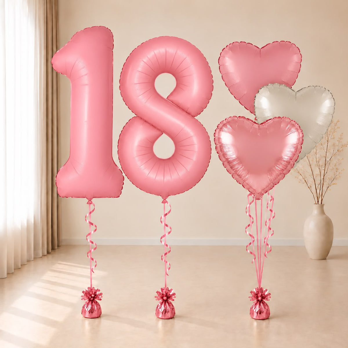 Composición de globos con números 18 rosas y corazones rosas y blanco, con cintas y contrapesos rosas.