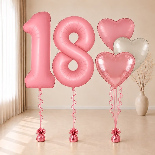 Composición de globos con números 18 rosas y corazones rosas y blanco, con cintas y contrapesos rosas.